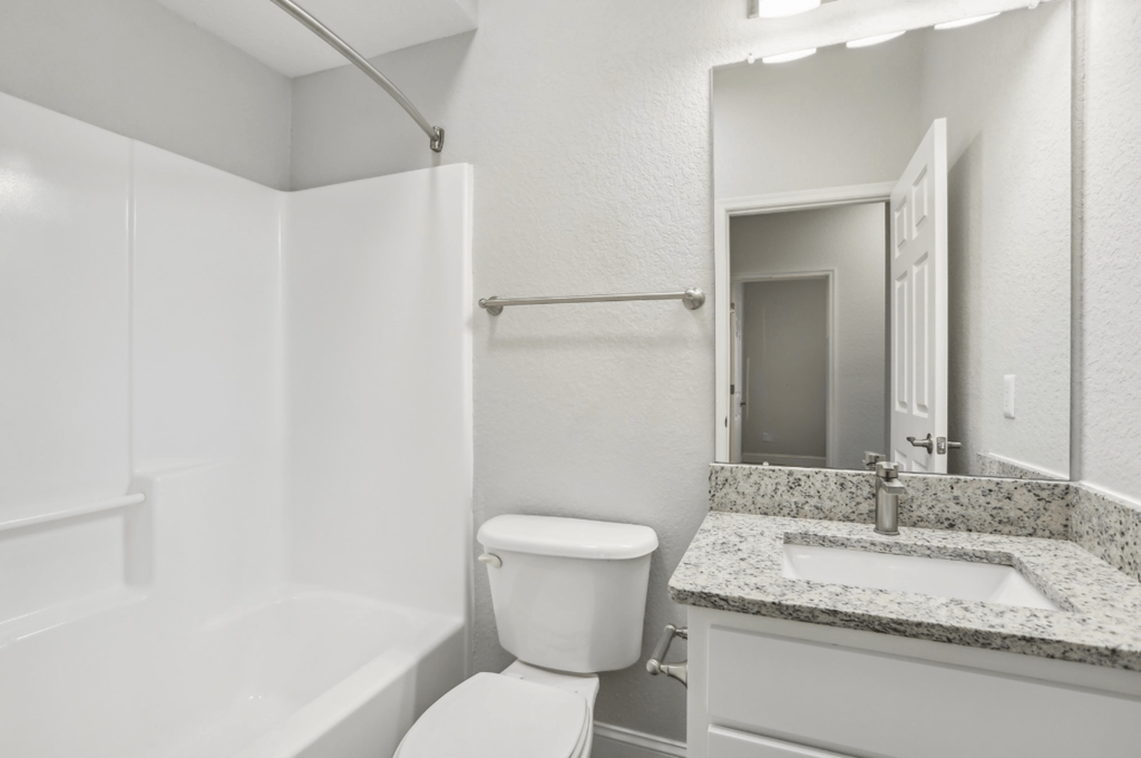 A white bathroom with a toilet, sink, and bathtub.